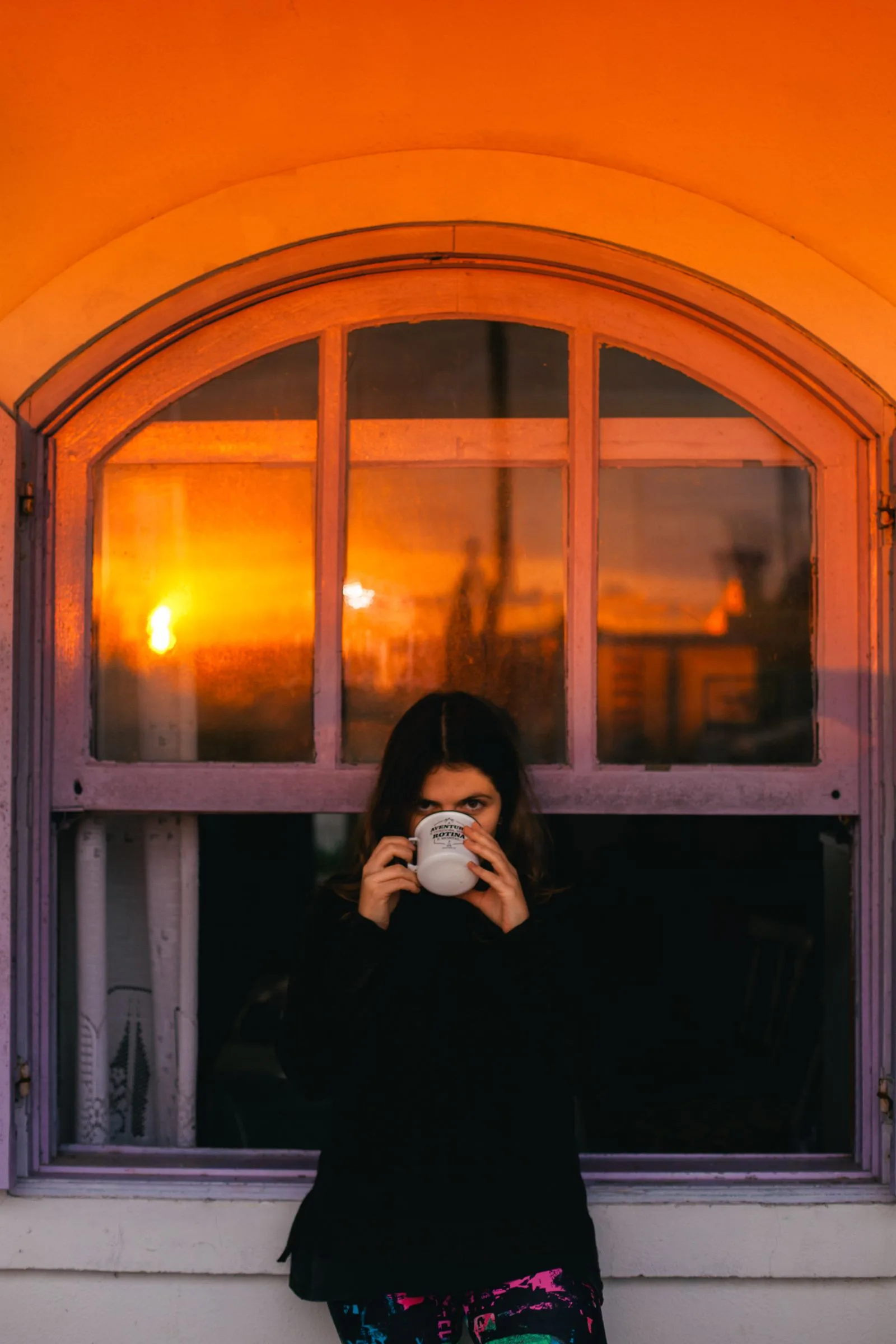 Coffee cup on a windowsill lit by early morning sunrise