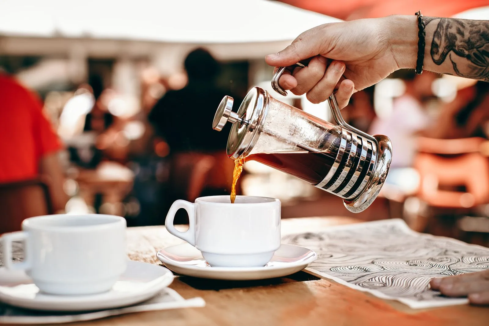 Slowly pouring brewed coffee from a french press into a cup