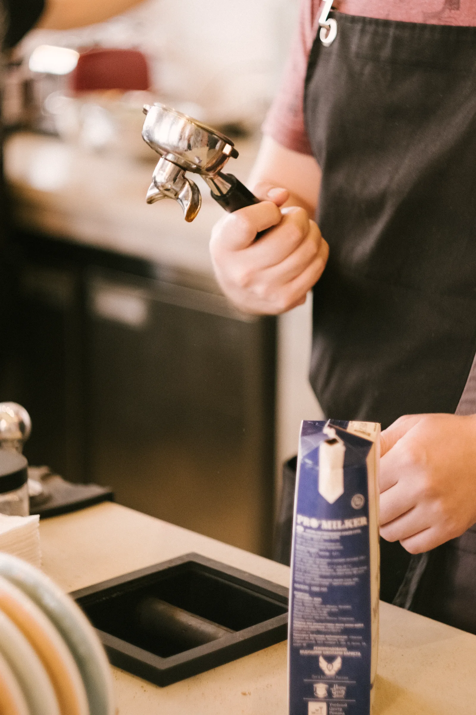 Technician descaling an espresso machine's group head with cleaning solution during maintenance routine