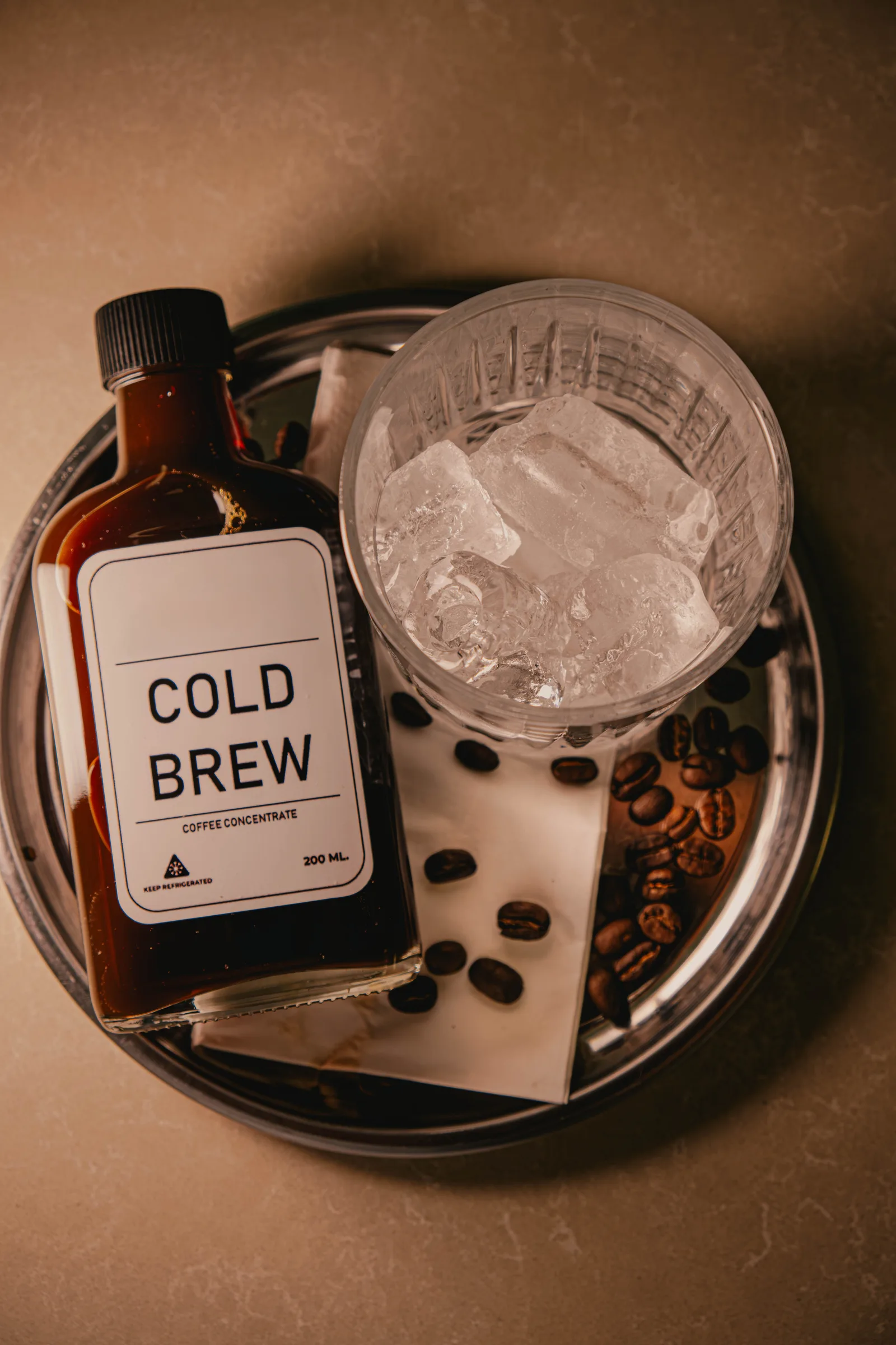 Cold brew concentrate poured over ice cubes in glass