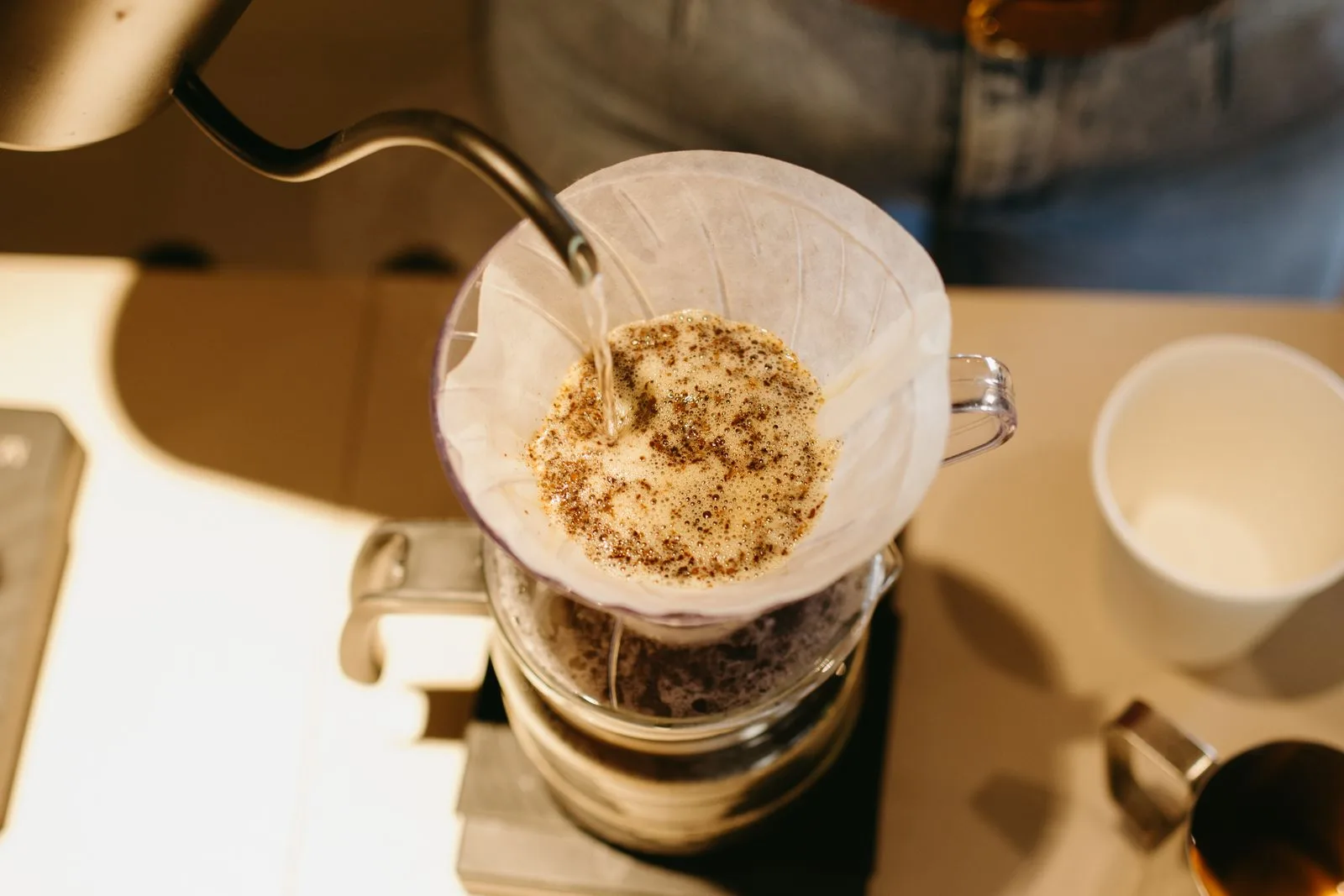 Hot water cascading over coffee grounds during bloom phase